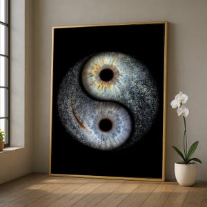 以下が含まれることがあります： 2 つのヒトの目からなる陰陽のデザインが特徴の額入りプリント。片方の目は青色で、もう片方は青と金色です。背景は黒で、フレームは金色です。