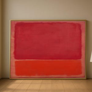 Könnte beinhalten: Ein gerahmtes abstraktes Gemälde mit einem goldenen Rahmen. Das Kunstwerk zeigt zwei horizontale Farbblöcke: ein großes, tiefrotes Rechteck über einem kleineren, leuchtend orange-roten Rechteck. Das Gemälde wird auf einem Holzboden präsentiert.