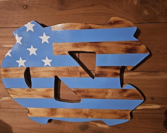 May include: A wooden wall cutout in the shape of the letters NC, featuring a painted design of horizontal light blue stripes alternating with stained wood grain stripes, and a light blue canton section decorated with five white stars.