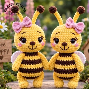 Puede incluir: Dos muñecos de abeja tejidos a ganchillo con cuerpos a rayas amarillas y marrones, ojos grandes y oscuros, antenas largas con puntas marrones y lazos rosas en la cabeza. El texto CROCHET PATTERN PDF English es visible en la esquina superior izquierda.