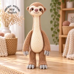 Puede incluir: Un muñeco perezoso de ganchillo con cuello largo, hilo marrón claro y crema, ojos oscuros, nariz rosa y garras grises. El texto CROCHET PATTERN PDF English es visible en la esquina superior izquierda de esta imagen.