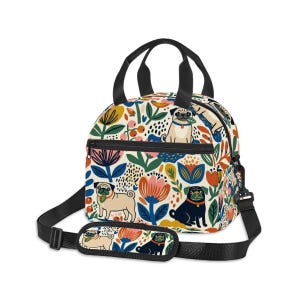 May include: A lunch bag featuring a cream-colored background with a repeating pattern of pugs, colorful stylized flowers, and leaves. The bag has black handles, a black zipper, and an adjustable black shoulder strap with a padded shoulder rest.