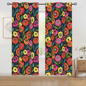 May include: Two floral print window curtains. The curtains feature a black background with a colorful pattern of red, orange, yellow, and pink flowers. The curtains are hanging in front of a window, with a wooden floor.