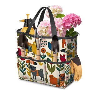 May include: A gardening tote bag with a colorful pug dog and floral pattern. The bag contains gardening tools, a spray bottle, flowers, and a pair of tan gloves. The tote has black handles and multiple pockets for storage.