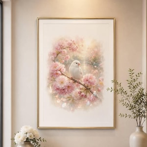 May include: A framed wall art print featuring a white bird perched on a branch surrounded by soft pink cherry blossoms. The artwork displays a watercolor style with a light, ethereal background, encased in a thin gold frame on a beige wall.