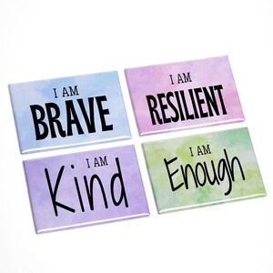 May include: Four rectangular magnets with inspirational phrases. Each magnet has a watercolor background in different colors: blue, pink, purple, and green. The phrases "I AM BRAVE", "I AM RESILIENT", "I AM KIND", and "I AM ENOUGH" are written in black.