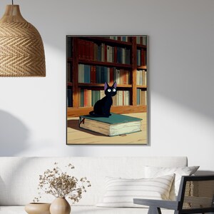 May include: A framed art print featuring a black cat with purple-tipped ears, sitting atop a large, open book. The cat is set against a backdrop of a library filled with books. The artwork has a cartoon style.