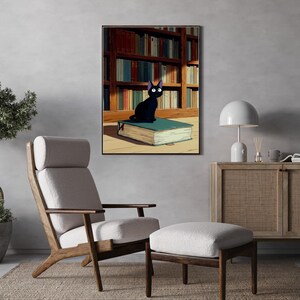 May include: A framed art print depicts a black cat with large white eyes sitting on a large book. The background shows a library with bookshelves. The print hangs above a mid-century modern chair and ottoman set.