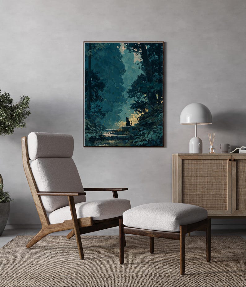 May include: A framed print shows a forest scene with a black cat on a stone path. The artwork hangs above a mid-century modern chair and ottoman set with light grey upholstery and a wooden frame. A white lamp and a wooden cabinet are also in the room.