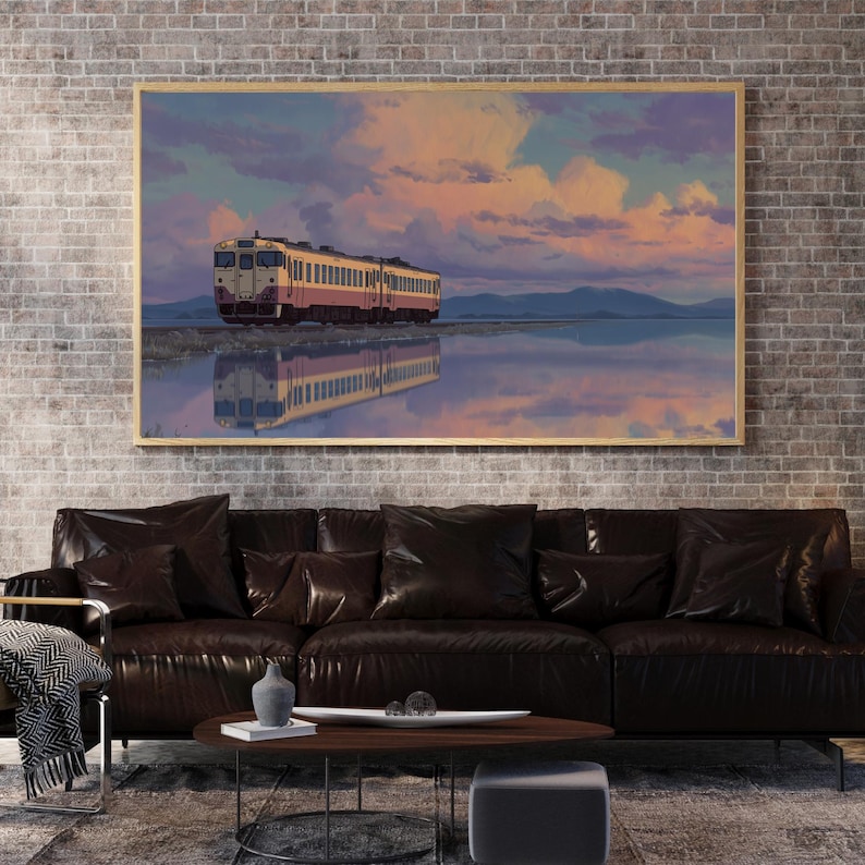 May include: A framed artwork depicts a train reflected in water under a colorful sky. The train is yellow and red, set against a backdrop of mountains and a sunset with pink and purple hues. The artwork is displayed above a dark brown leather sofa.