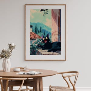 May include: Framed art print featuring a black cat with wide eyes, lounging on a stone ledge. The background depicts a scenic view of mountains, trees, and buildings, with a light blue sky. The artwork has a cartoon style.