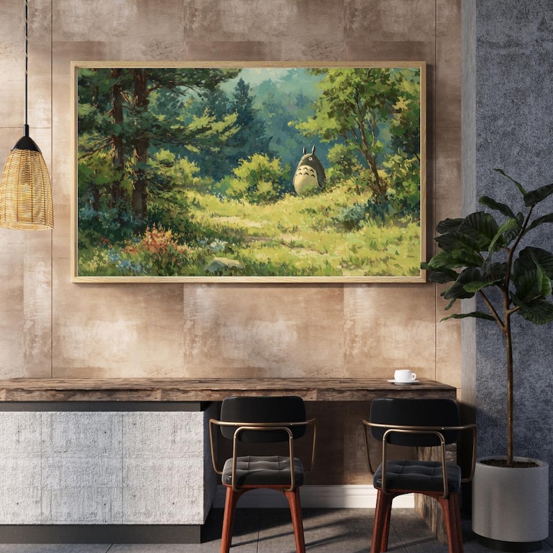 May include: A framed art print depicting a forest scene with a large, round, gray creature. The artwork features lush green trees, a grassy path, and a light-filled clearing. The print is displayed above a wooden desk with two chairs.