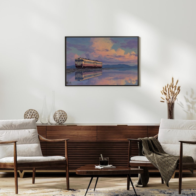 May include: A framed art print depicts a train reflected in calm water under a colorful sky. The train is white and red, set against a backdrop of pink, purple, and blue clouds. The artwork is displayed above a mid-century modern style wooden cabinet.