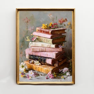 May include: A framed artwork featuring a stack of vintage books in various colors, including pink, brown, and cream. The books are adorned with small flowers, creating a still-life composition. The frame is gold.