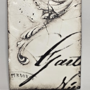 Könnte beinhalten: Rechteckige, cremefarbene Keramikfliese mit rissiger Oberfläche. Die Fliese zeigt ein abstraktes Schwarz-Weiß-Design mit dem Wort "Vant" in einer Schriftart. Das Wort "PERNOV" ist ebenfalls sichtbar.