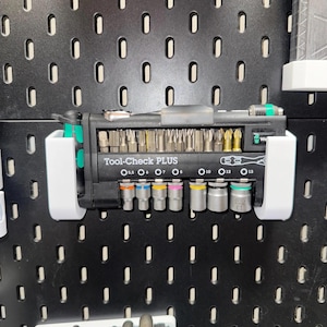 May include: A black Wera Tool-Check PLUS bit and socket set mounted in a white plastic holder. The set features a row of various metal screwdriver bits and a row of sockets with colored rings, labeled with sizes 5.5, 6, 7, 8, 10, 12, and 13.