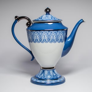 May include: A blue and white porcelain teapot with a decorative design. The teapot has a silver handle and trim, and a matching lid. The teapot is approximately 10 inches tall.
