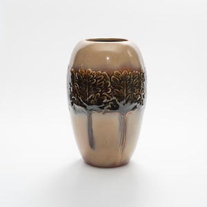 May include: A ceramic vase with a brown and tan color scheme. The upper portion is a glossy brown, while the lower part is tan. A band of dark brown, stylized tree designs encircles the middle. The vase has a rounded, oval shape.