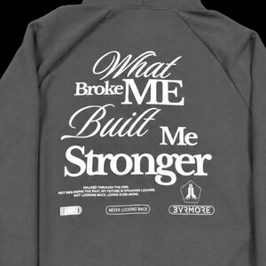 May include: A charcoal gray hooded sweatshirt featuring white text on the back that reads: What Broke ME Built Me Stronger, along with smaller text including Walked Through The Fire, Never Looking Back, and the brand name 3VRMORE in a pentagon.