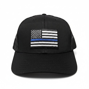 May include: Black baseball cap with a mesh back and a curved brim. The cap features a patch with a stylized American flag design, including a blue line. The flag has white stripes and stars, and a blue stripe.