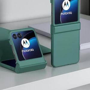 May include: Green protective phone case for a Motorola foldable phone. The case is shown in two positions: open and closed. The phone screen displays the Motorola logo. The case is a solid, matte green color.