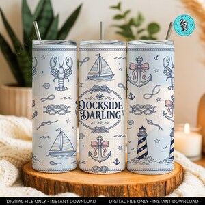 Puede incluir: Un juego de tres vasos de acero inoxidable con diseños náuticos. Cada vaso presenta un fondo azul claro con ilustraciones de veleros, anclas, langostas y el texto "Dockside Darling". Los vasos incluyen una pajita plateada.