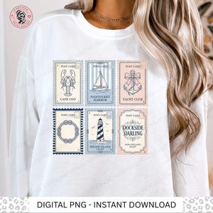 Op de afbeelding: Witte sweatshirt met vintage ansichtkaarten met nautische thema's. Elke ansichtkaart toont illustraties van een kreeft, zeilboot, anker, touwkrans, vuurtoren en de teksten "Cape Cod", "Nantucket Harbor", "Yacht Club", "Rhode Island Light" en "Dockside Darling".