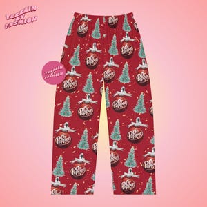 May include: Red pajama pants with a repeating pattern of Dr. Pepper ornaments and Christmas trees. The ornaments have a white bow and the Dr. Pepper logo. The pajama pants have an elastic waistband.