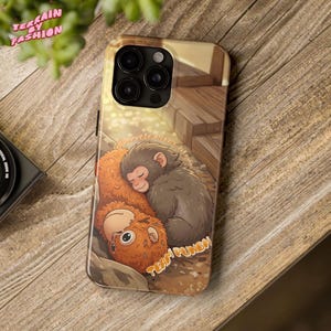 May include: A phone case featuring a cartoon illustration of two monkeys cuddling. One monkey is brown and the other is orange. The text "Team Munch" is visible. The background has a wooden texture.