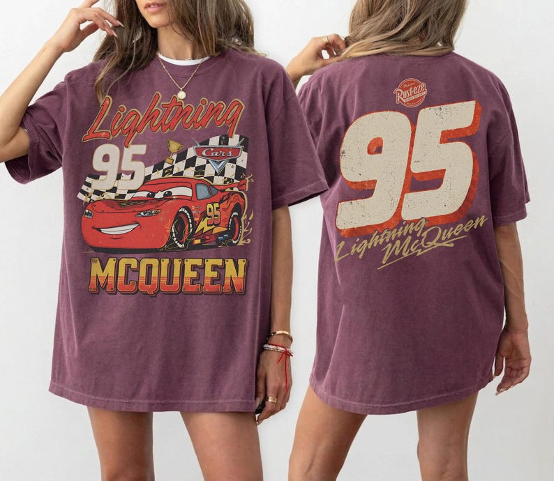 May include: A maroon t-shirt featuring a graphic of Lightning McQueen from the movie Cars. The front design includes the text "Lightning 95 McQueen" with an image of the race car. The back of the shirt displays a large "95" and "Lightning McQueen" text.