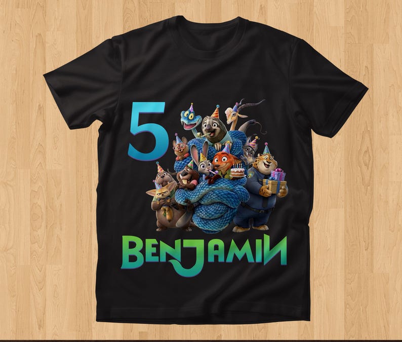 May include: Black t-shirt featuring a colorful graphic of cartoon animals, a blue number 5, and the name BENJAMIN in green and blue. The design includes characters with party hats and gifts, suitable for a birthday celebration.