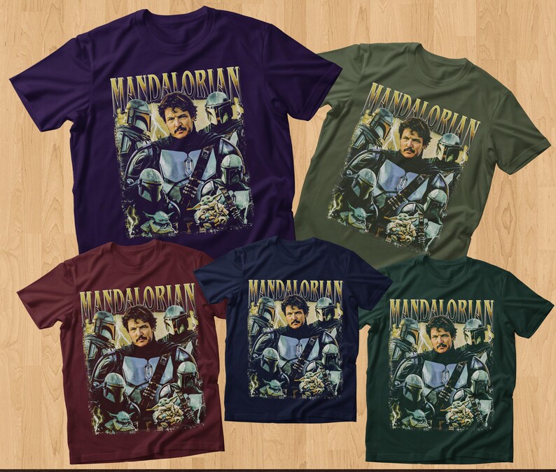 May include: Five short-sleeved t-shirts in various colors: purple, olive green, burgundy, navy blue, and dark green. Each shirt features a graphic of a man and several figures in helmets, with the word "MANDALORIAN" in gold lettering.
