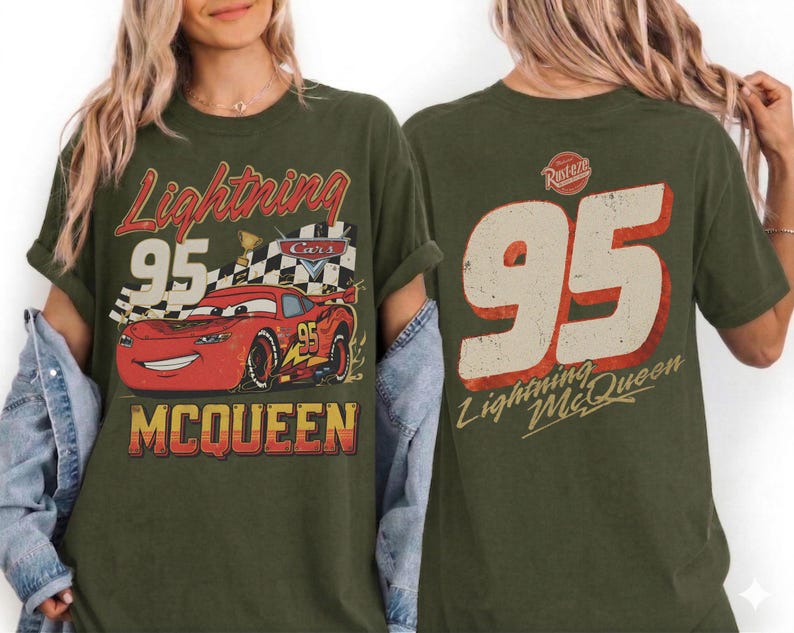 May include: Olive green t-shirt featuring a distressed graphic of Lightning McQueen from the movie Cars. The front design includes the number 95, a checkered flag, and the name "McQueen." The back of the shirt displays a large number 95 and the text "Lightning McQueen."