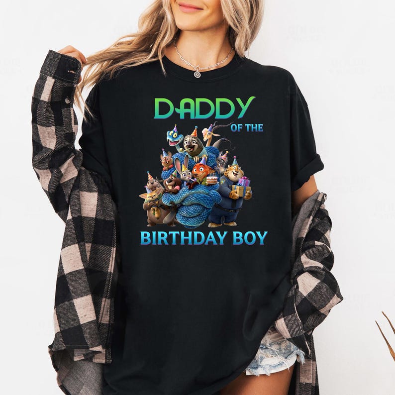 May include: Black t-shirt with the text "DADDY OF THE BIRTHDAY BOY" in green and blue. The shirt features a colorful graphic of cartoon characters. The shirt is a crew neck and has short sleeves.