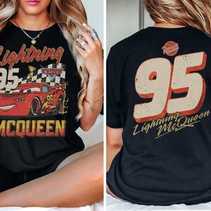 May include: Black t-shirt featuring a graphic of Lightning McQueen from the Cars movie. The front design includes the number 95, the words "Lightning McQueen," and a checkered flag. The back of the shirt displays the number 95 and the words "Lightning McQueen."