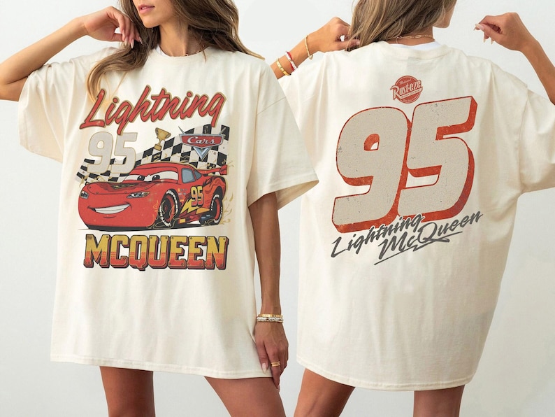 May include: Cream-colored t-shirt featuring a graphic of Lightning McQueen from the movie Cars. The front displays the car, the number 95, and the text "Lightning McQueen". The back shows a large number 95 and the text "Lightning McQueen".
