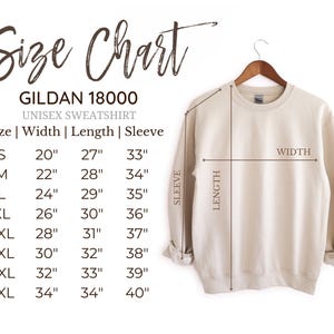 May include: A cream-colored Gildan 18000 unisex sweatshirt hanging on a wooden hanger. The image includes a size chart with measurements in inches for width, length, and sleeve length, ranging from size small to 5XL.