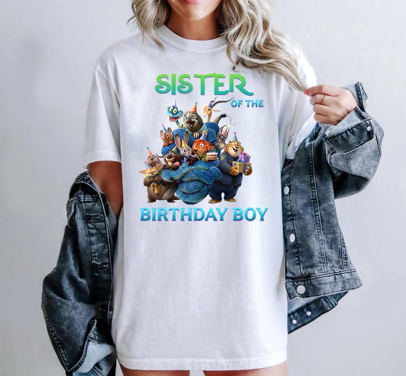 May include: White t-shirt with a colorful graphic of cartoon animals and the text "SISTER OF THE BIRTHDAY BOY" in green and blue. The design features various animal characters in party hats.