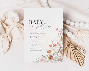 Op de afbeelding: Een uitnodiging voor een babyshower met de tekst "BABY in bloom" in zwart schrift. De uitnodiging bevat bloemenillustraties in tinten oranje, roze en wit. De details omvatten de naam "ELENA", datum, tijd en locatie.