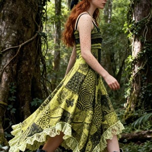 以下が含まれることがあります： 幾何学模様と花柄の黒いアクセントとレースの裾が付いた、模様入りのライムグリーンのドレスを着た女性が森の中を歩いています。 彼女はヘッドスカーフと青いカウボーイブーツを履いています。