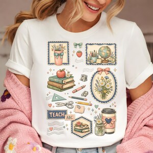 May include: White t-shirt with various school-themed illustrations. Designs include books, flowers, a globe, pencils, and the text "TEACH ABC". The shirt has a crew neck and short sleeves.