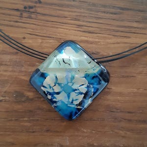 May include: A blue and white glass pendant with a black cord necklace. The pendant is a diamond shape with a swirling pattern.