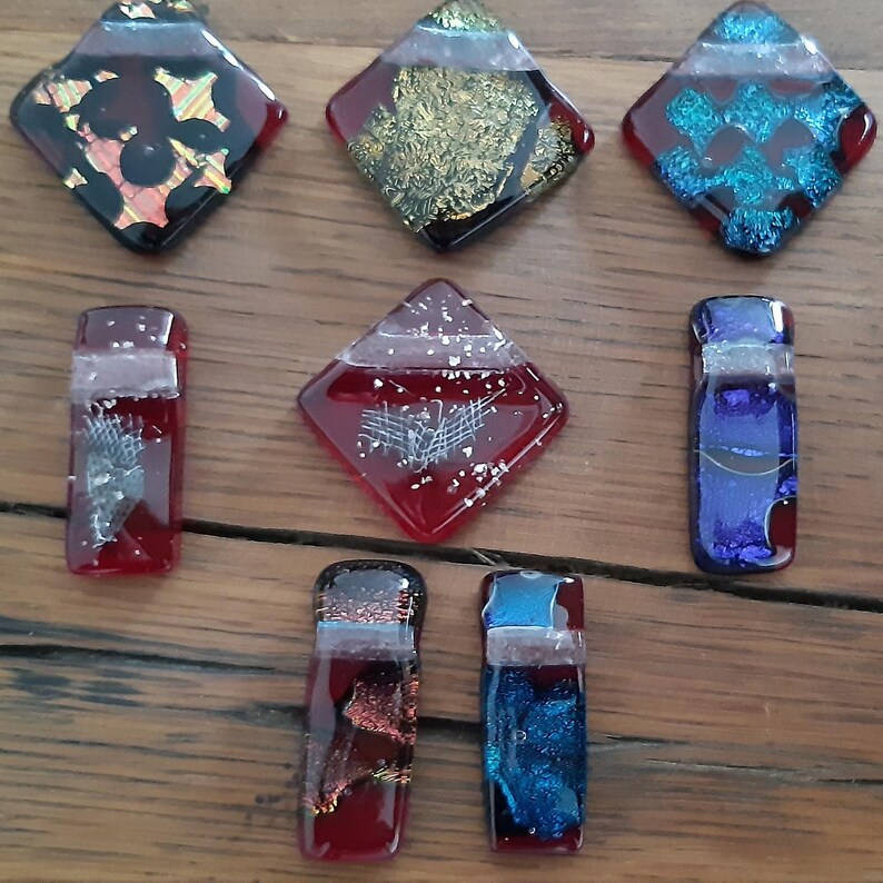 May include: Assortment of eight small glass tiles in various colours and patterns. The tiles are in the shape of squares and rectangles. Some of the tiles have a metallic finish.