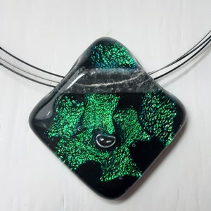 May include: A black and green glass pendant with a diamond shape and iridescent finish. The pendant is on a silver chain.