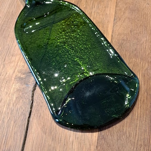 May include: A green glass bottle shaped serving tray. The tray is made from recycled glass and has a unique, organic shape.