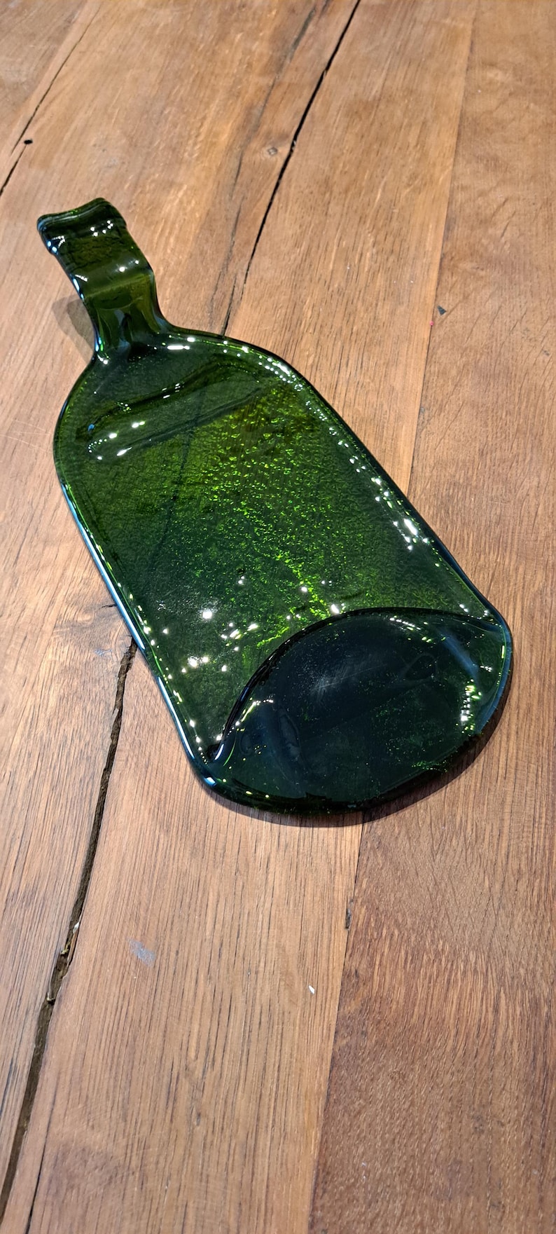 May include: A green glass bottle shaped serving tray. The tray is made from recycled glass and has a unique, organic shape.