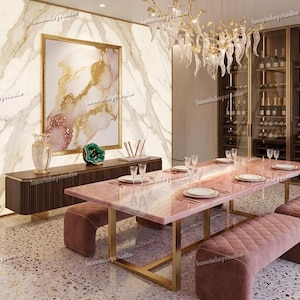 May include: A luxurious dining room featuring a pink marble table with gold legs, complemented by matching benches. The room includes a wine cabinet, a decorative wall art piece, and a chandelier. The floor is a speckled terrazzo.