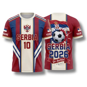 Könnte beinhalten: Ein rot-weiß-blaues Serbien-Fußballtrikot mit der Aufschrift "SERBIA 10" auf der Vorderseite. Auf der Rückseite sind ein Fußball, die serbische Flagge und der Text "SERBIA 2026 Go Serbia!" zu sehen.