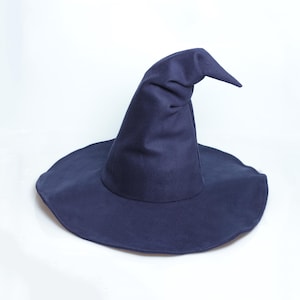 Op de afbeelding: Een donkerblauwe heksenhoed met een brede, ronde rand en een hoge, puntige kroon die aan de bovenkant licht gebogen is. De hoed is gemaakt van een gladde, effen stof met een consistente, matte afwerking over het gehele oppervlak.