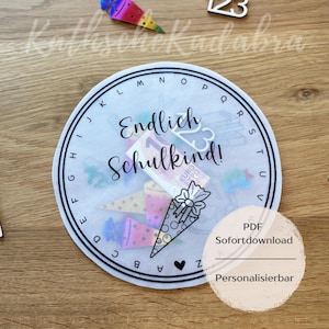 May include: A circular, transparent design with the text "Endlich Schulkind!" and a decorative school cone. The design is surrounded by an alphabet border and includes a PDF download option.
